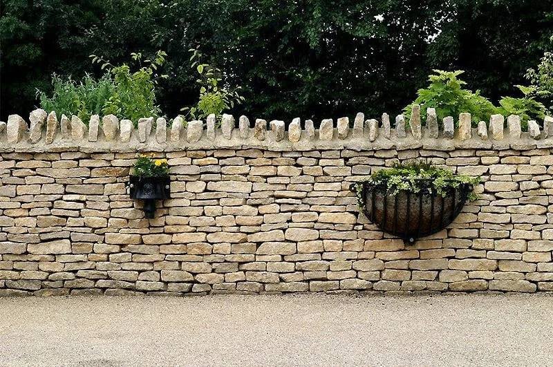 Dry stone garden wall with planted borders, cleaned of moss